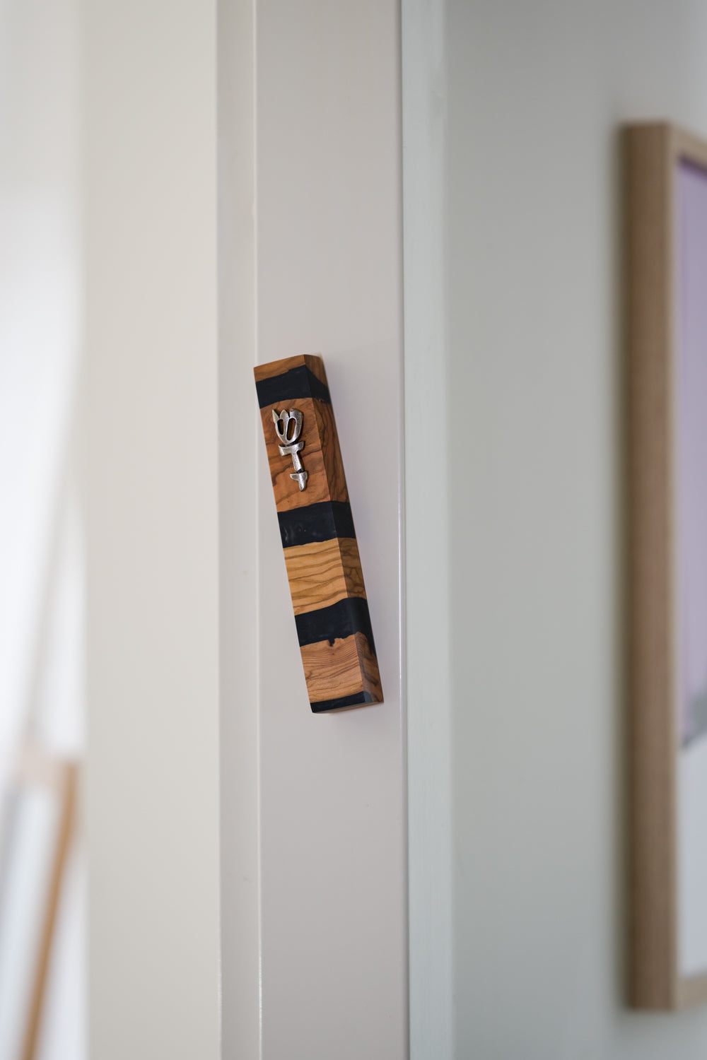 Handmade wooden and black resin mezuzah case on a doorpost, placed by the Jewish tradition.