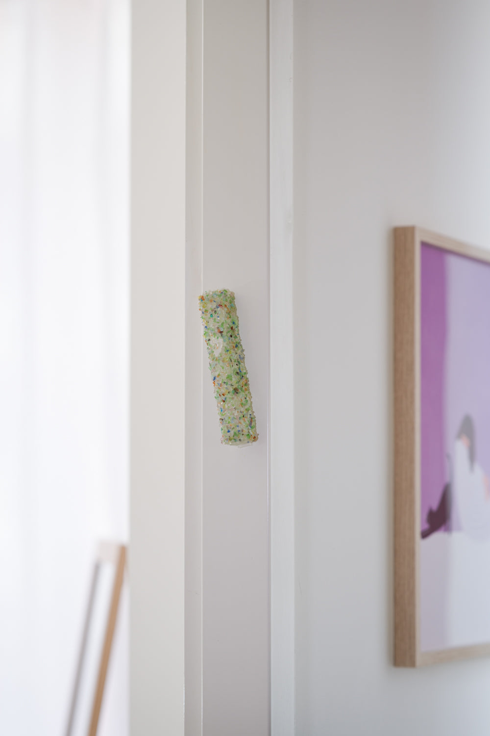 Handmade crystal green mezuzah case on a doorpost, placed by the Jewish tradition.
