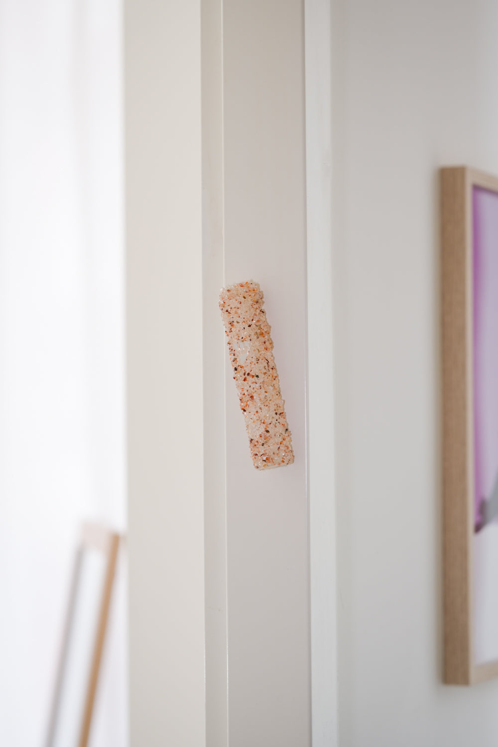 Handmade crystal orange mezuzah case on a doorpost, placed by the Jewish tradition.