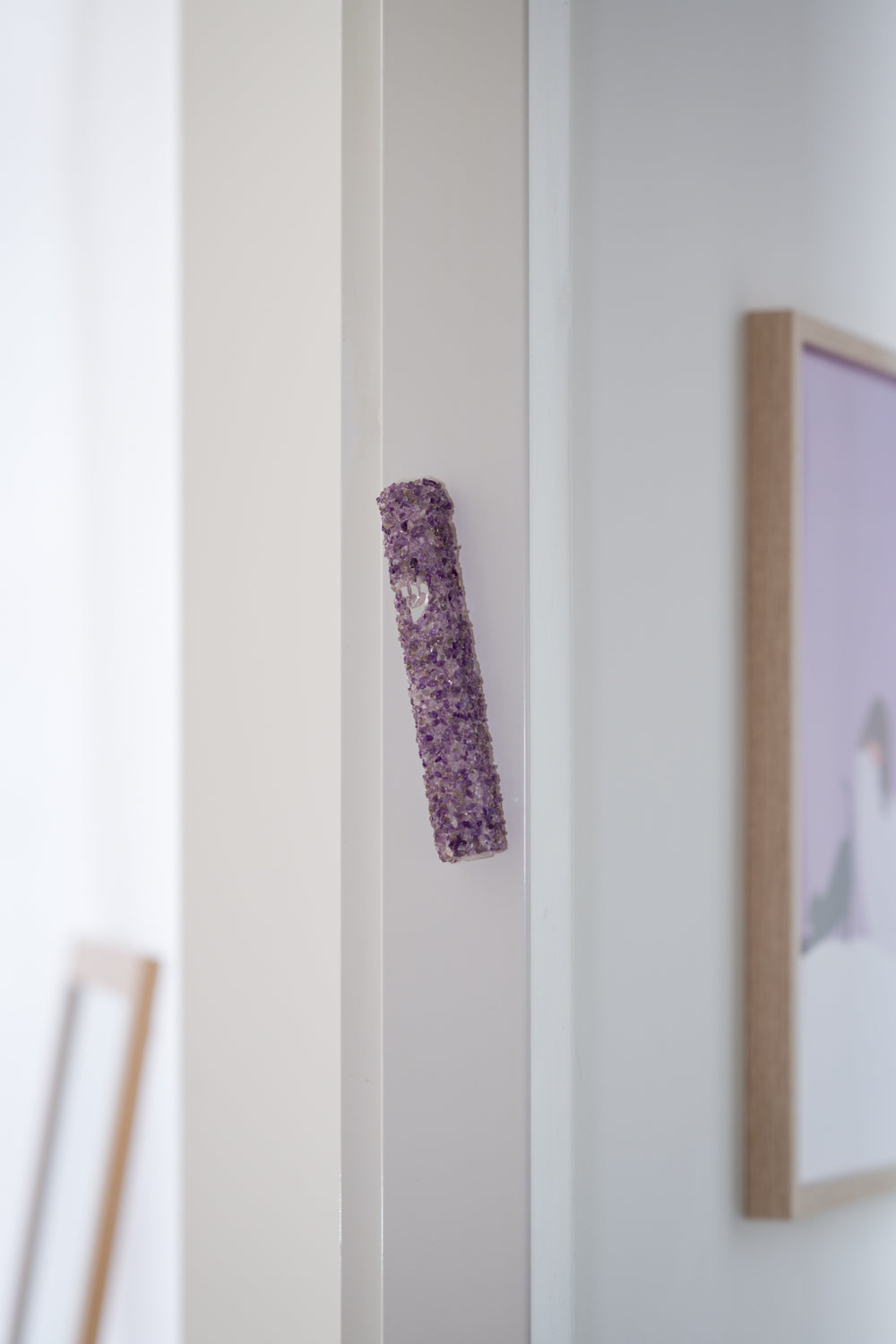 Handmade crystal purple mezuzah case on a doorpost, placed by the Jewish tradition.