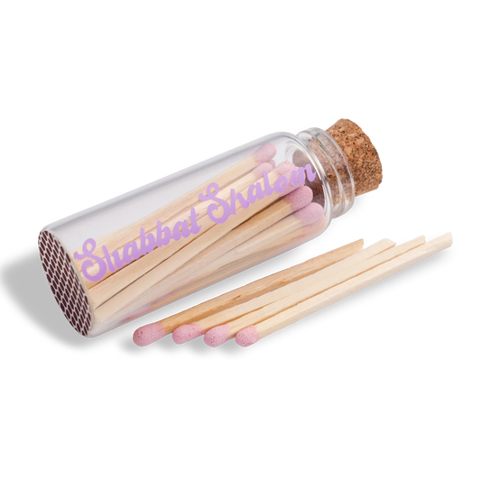 Handmade glass jar with cork lid filled with pink-tipped matches, labeled “Shabbat Shalom” 