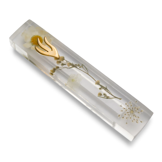 Handmade mezuzah crafted from clear resin and white preserved flowers, featuring a golden Shin symbol on the front.