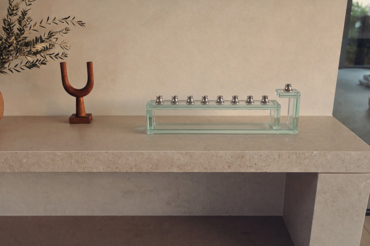 Handmade glass Hanukkah menorah with nine silver cups on a stone shelf