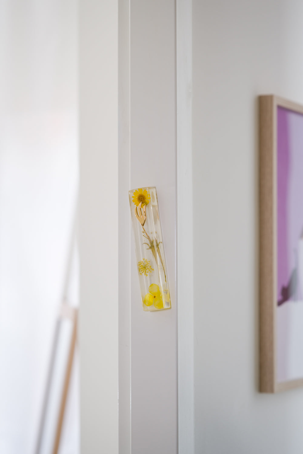 Handmade yellow floral mezuzah case on a doorpost, placed by the Jewish tradition.